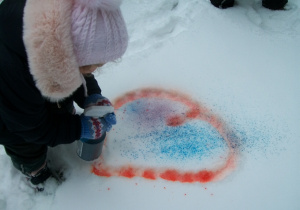 Dzieci wyposażone w spryskiwacze do wody z kolorowymi barwnikami tworzą na śniegu kolorowe obrazy
